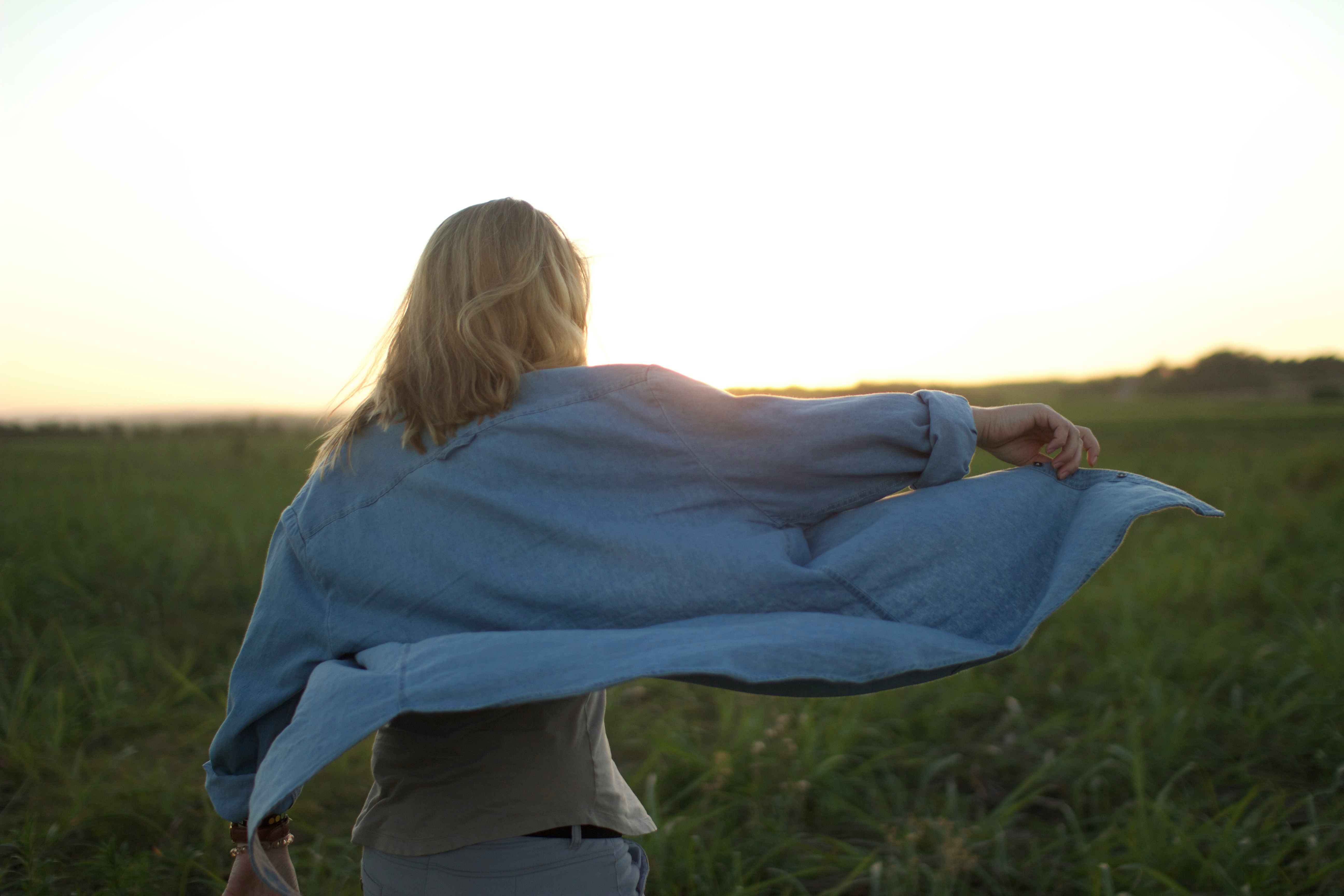 woman walking in the middle of grass field